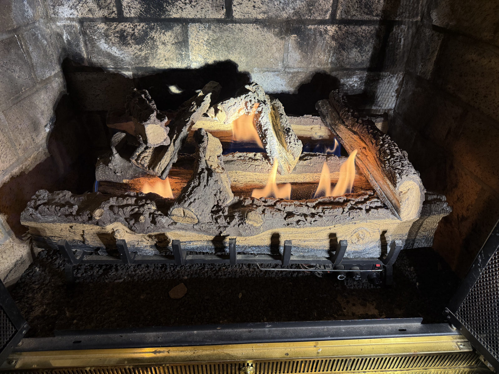 Gas log fireplace with flames burning in brick firebox